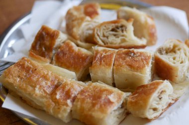 Taze pişmiş börekler tepside otururken parçalara ayrılır..