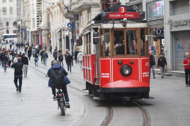 Kırmızı tramvaylı ve bisikletli kalabalık arasında sallanan hareketli bir cadde..