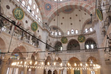 Ziyaretçiler büyük camideki karmaşık tasarımlara ve asılan lambalara hayran..