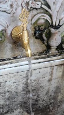 Pirinç çeşme yaş ile rustik bir taş zemin üzerine su döker.