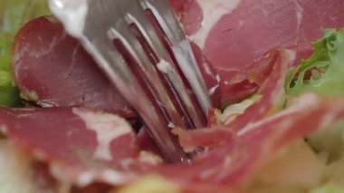 Etli canlı bir salataya delen çatalın yakın çekimi..