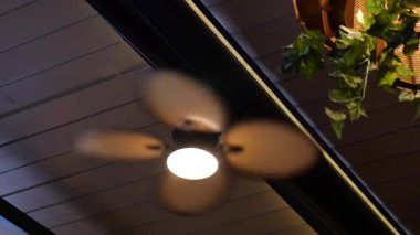 Sıcak ışık altında dönen bir tavan vantilatörü akşam havasını yükseltir..