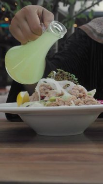 Bir el canlı bir lokantada renkli bir salatanın üzerine keskin bir sos döker..