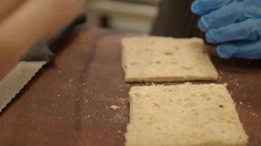 Uzman eller sıcak bir mutfak ortamında taze ekmeği bıçakla dilimler..