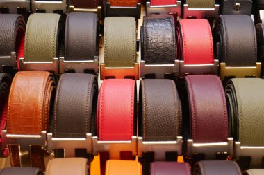 Perakende satış ortamında düzgün bir şekilde düzenlenmiş kemerlerin farklı stil ve renkleri.