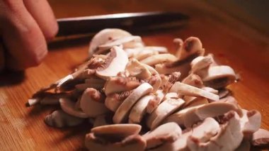 Yemek hazırlamak için sıcacık bir mutfakta taze mantar dilimliyorum..