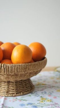 Parlak portakallarla dolu bir hasır sepet renkli bir masa örtüsünün üzerinde duruyor..