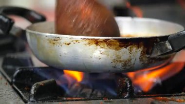 Bir aşçı yemek pişirirken sıcak bir tavayla yemek hazırlar..