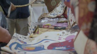Alışverişçiler canlı bir piyasa gösterisinde renkli kumaşlara hayran kalırlar..
