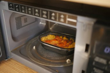 Donmuş yemek, öğle yemeği sırasında mikrodalga fırında ısıtılıyor..