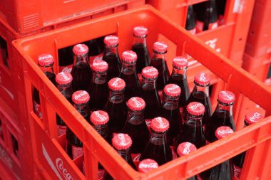 Hindi İstanbul 25 Haziran 2025. Kırmızı sandıkların içinde klasik cam Coca Cola şişeleri bir araya toplanmış..