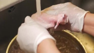 Bir insan yemek pişirmeden önce lavaboda çiğ tavuk yıkar..