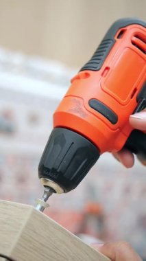 Bir insan vidaları tahtaya tutturmak için kablosuz matkap kullanır..