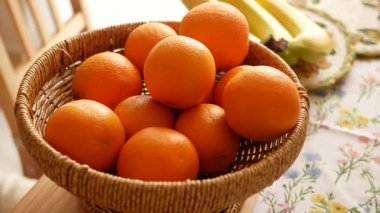 Olgun portakallarla dolu bir sepet muzların yanındaki mutfak masasında duruyor..