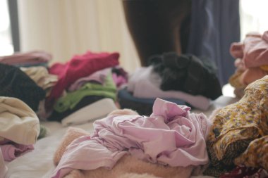 Giysiler, birileri eşyaları düzenlerken bir yüzeye saçılmış..