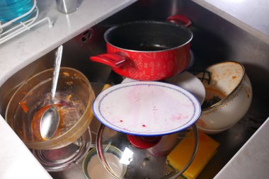 Kirli bulaşık ve tencere yığını mutfak lavabosu alanını dolduruyor..