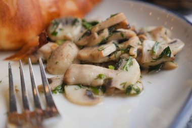 Ekmek rulosunun yanında otlarla süslenmiş mantar dilimleri..