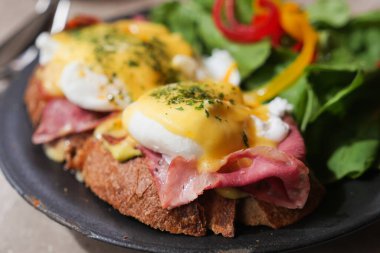 İki yumurtalı Benedict tost ekmeği, yanında yeşiller ve renkli biberler..