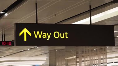 Bir havaalanı ayarında gezginlerin çıkış yolunu gösteren açık tabela.