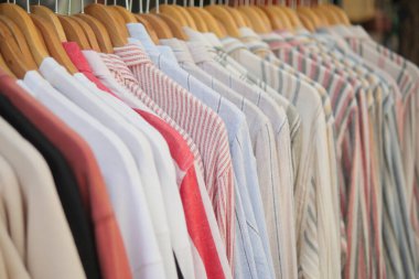 Bir mağazadaki askılara çeşitli gömlekler asılıyor..