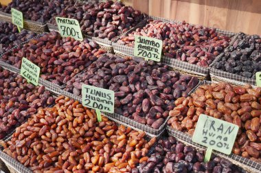 Kalabalık bir pazarda sepetlerde düzenlenmiş farklı tarih türleri.