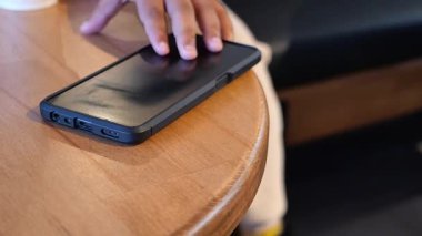 Bir kafede ahşap bir masanın üzerine sıcak bir ortam olan bir telefon yerleştirilir..