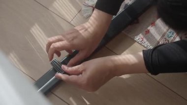 Bir ev eşyasını ahşap zeminde birleştiren ellerin yakın çekimi..