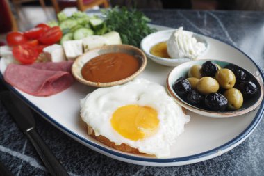 Sebzeli, zeytinli, peynirli ve kızarmış yumurtalı renkli bir kahvaltı tabağı..