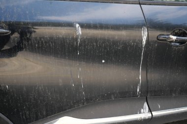 Açık hava kullanımından sonra siyah bir arabanın kapısında toprak ve çizikler görülüyor..