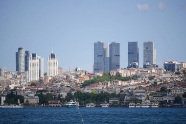 Aşağıda tekneleri olan modern binalar kıyı şehrinin üzerinde yükseliyor..