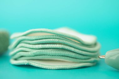 Yeniden kullanılabilir pamuk pedleri parlak bir turkuaz yüzeyde dinleniyor..