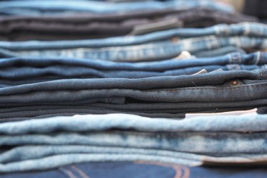 Kot pantolonun çeşitli tonları bir mağazada organize bir şekilde sergilenmektedir..