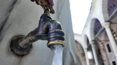 Bir el eşsiz bir avluda antika bir su musluğu işletiyor..