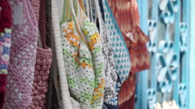 Değişik renklerde el yapımı çantalar canlı bir pazar ortamında asılı duruyor..
