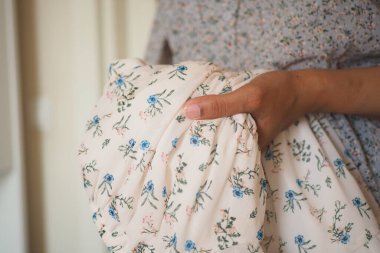 Bir insan narin desenli bir çiçek kumaşını kavrıyor..