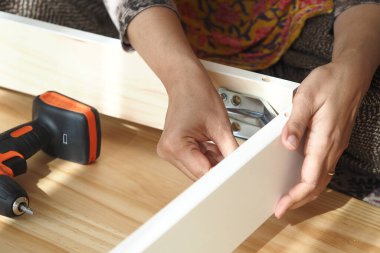 Bir kişi evde mobilya montajı yaparken ustalıkla donanım yükler.