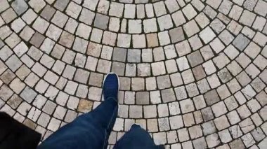 Bireyler dairesel kaldırım taşı yolu boyunca yürür, ayrıntıları gösterir..