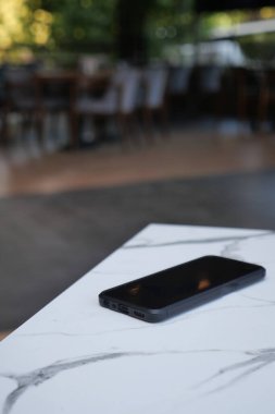 Restorandaki mermer masada dinlenen siyah akıllı telefon. Akıllı telefon kavramını kaybettim,
