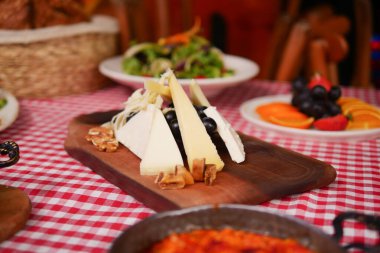 Neşeli bir toplantıda taze meyvelerle servis edilen çeşitli peynirler..