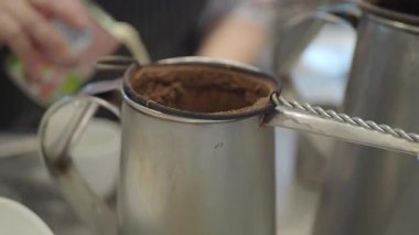 Sıcak bir kafede geleneksel bir teknikle kahve demleme sanatını keşfedin..