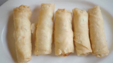 Sıcak bir lokantada beyaz bir tabakta servis edilen taze pişmiş börekler..