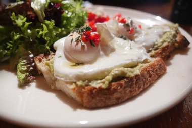 Üstünde haşlanmış yumurta ve canlı salata sebzeleri olan bir tabak..