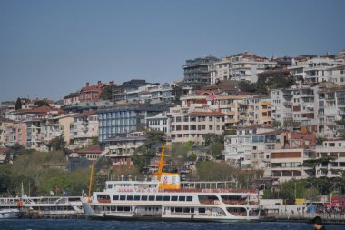 Arkasında canlı bir şehir olan bir feribot denize açılıyor..