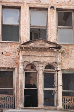 İhmal edilmiş yapılar boya soyarken ve geçmişteki ihtişamın kırık camlarını gösteriyor..