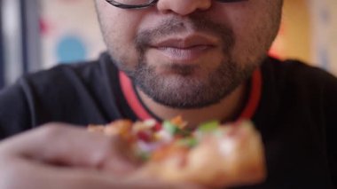 Taze malzemelerle dolu bir dilim pizzanın tadını çıkaran biri..