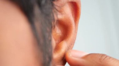 Kulağını kaşıyan birinin yakın çekimi.,