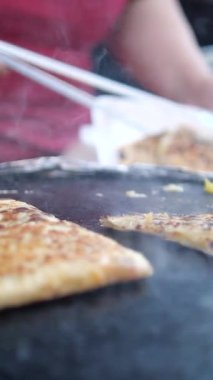 Bir sokak satıcısı sıcak ızgarada taze ekmek hazırlar. Lezzetli bir ziyafet yaratır..