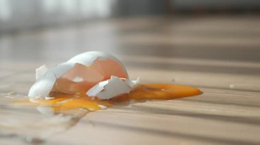 Tahta zeminde kırılmış bir yumurta kabuğu güneşe dökülür..