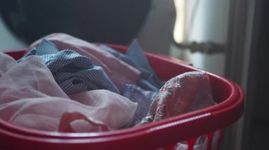 Konforlu bir evde çeşitli kıyafetlerle dolu bir çamaşır sepetinin manzarası..