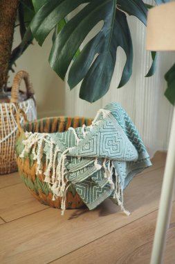 Örülmüş sepet, büyük bir bitkinin yanında şık bir battaniye tutar..